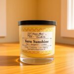 A medium sized Yuzu Sunshine soy wax candle sitting on a wooden table with sunlight shining in through windows.